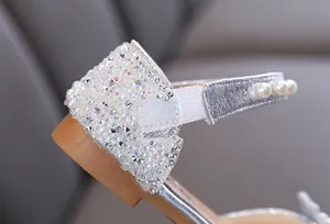 Detailed macro view of girl's silver princess shoe with sparkling rhinestones and pearls