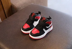 Gros plan de baskets montantes pour enfants rouge et noir sur un banc en cuir marron
