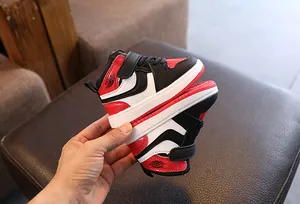 Détail de baskets montantes pour enfants en rouge, noir et blanc avec patte auto-agrippante