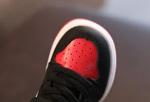 Gros plan sur la zone des orteils en cuir rouge perforé de ces baskets montantes pour enfants