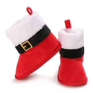 Primer plano de botas de Navidad de felpa roja para bebé con ribete blanco y cinturón