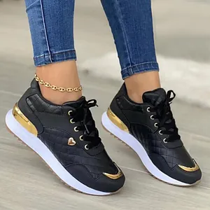 Detail view of black quilted women's sneakers featuring gold heart and metallic accents