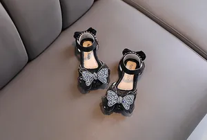 Vue détaillée de chaussures princesse noires pour filles avec des nœuds papillon en cristal.