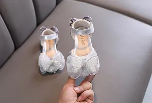 Détail d'une chaussure de princesse argentée pour fille avec un nœud papillon très scintillant