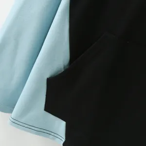 Close-up detail of color block hoodie showing blue sleeve and black kangaroo pocket