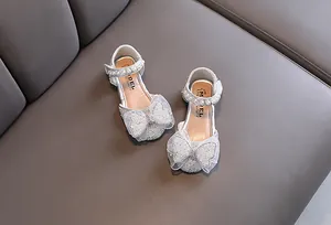 Close-up of girls' silver princess shoes with sparkling rhinestone bow and pearl strap