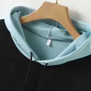 Close-up detail of a men's light blue and black color-block hoodie on a hanger