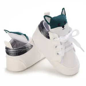Detalle de zapato suave de bebé para primeros pasos con lengüeta de zorro verde.