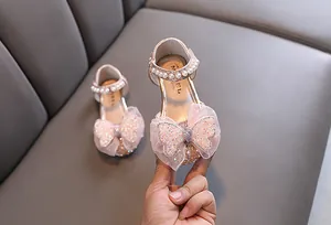 Elegant pink girls princess shoes decorated with a sparkling butterfly bow and pearl strap