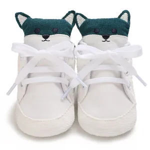 Vista frontal de lindos zapatos de pana para bebé en blanco y verde con bordado