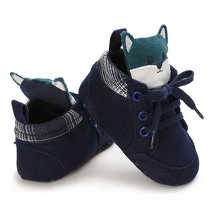 Detalle de zapatos para bebé de pana azul con diseño de lobo animado en la lengüeta