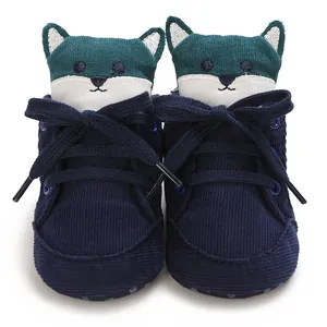 Primer plano de zapatos de bebé azul marino con decoración de zorro de tela verde.
