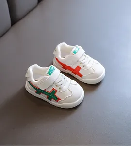 Nahaufnahme von weißen Lauflernschuhen mit rot-grünen Streifen und weichen Sohlen.
