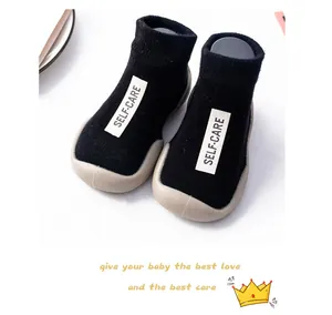 Detail view of soft black knitted baby walker sock shoes with white self-care label