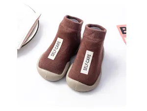Detailed view of the brown knit baby sock shoes featuring soft soles and SELF-CARE label.
