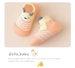 Nahaufnahme von orange gestreiften Babysöckchen mit süßem Rentier-Cartoon-Design