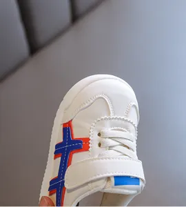 Nahaufnahme von weißen Lauflernschuhen mit rot-blauen Seitenstreifen und Klettverschluss