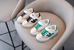 Zapatillas de malla transpirable para niños en colores verde y negro sobre una silla gris