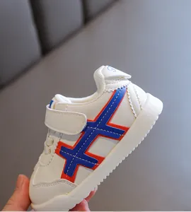Nahaufnahme eines weißen Babylernschuhs mit rot-blauem Kreuzmuster und weicher Sohle