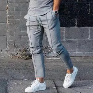 Trendy men's grey casual jogger pants featuring vertical seam detail and white sneakers