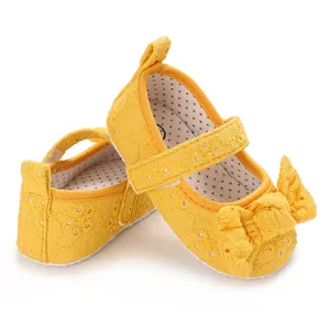 Gros plan sur des chaussures bébé Mary Jane jaunes brodées avec un grand nœud décoratif