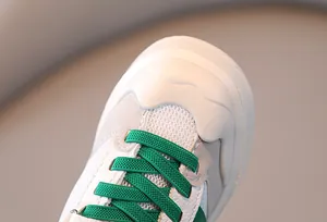 Primer plano de zapatilla transpirable para niños con cordones verdes y puntera.