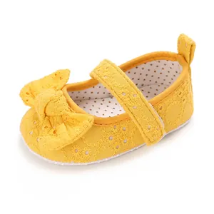 Détail d'une chaussure de princesse jaune brodée pour bébé avec un joli nœud dentelle