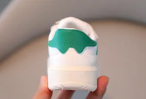 Primer plano del talón de zapatillas infantiles en blanco y verde con suela blanda cómoda.