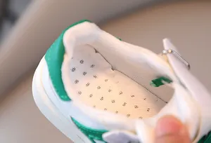 Primer plano del forro de malla transpirable y plantilla de zapatillas verdes infantiles.