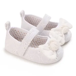 Détail de chaussures de princesse pour bébé en dentelle blanche avec un grand nœud décoratif