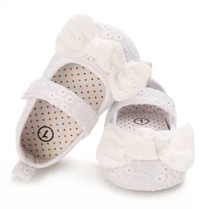 Vue détaillée de chaussures de princesse pour bébé en dentelle blanche avec un grand nœud