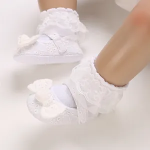 Détail des chaussures de princesse en dentelle blanche avec nœuds et chaussettes à volants