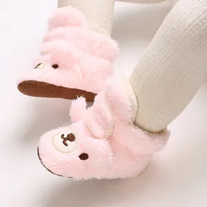 Detailaufnahme von flauschigen rosa Babyschuhen mit süßem Bärengesicht und Sohle.
