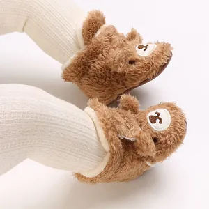 Nahaufnahme von niedlichen braunen Plüsch-Babyschuhen mit weißen Rippstrumpfhosen