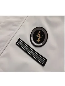 Detailopname van stijlvolle geborduurde patches op een beige heren vrijetijdsparka