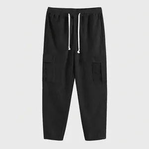 Dettaglio dei pantaloni cargo neri in velluto a coste con coulisse e tasche laterali