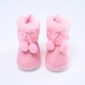 Detailansicht von weichen rosa Plüsch-Babyschuhen mit niedlichen Bommel-Akzenten