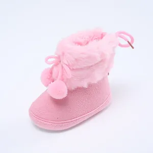 Nahaufnahme von weichen rosa Baby-Winterstiefeln mit Kunstfellbesatz und niedlichen Pompons.