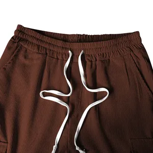 Dettaglio dei pantaloni in velluto a coste marroni con vita elastica e coulisse bianca