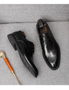 Vue détaillée de chaussures derby en cuir noir avec texture crocodile sur fond gris