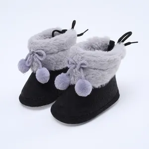 Nahaufnahme von Baby-Winterschuhen mit Pelzbesatz und lavendelfarbenen Bommeln