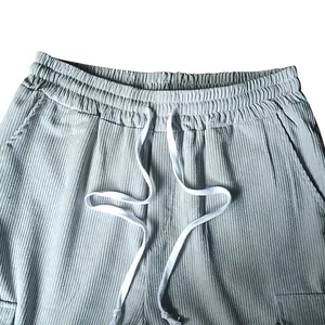 Dettaglio di pantaloni in velluto a coste grigi da uomo con vita a coulisse