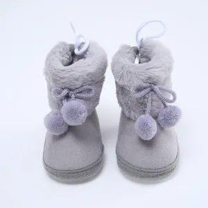 Nahaufnahme von grauen Baby-Winterstiefeln mit weichem Kunstfell und Zier-Pompons