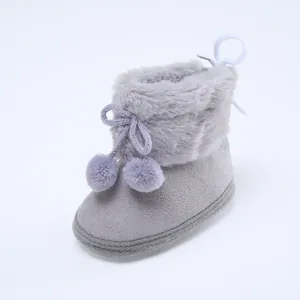 Nahaufnahme der grauen Baby-Winterstiefel mit weichem Pelzbesatz und dekorativen Pompons