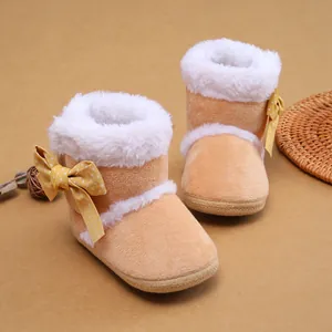 Nahaufnahme süßer pfirsichfarbener Baby-Plüschstiefel mit Pelzfutter und Schleife