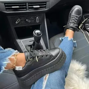 Detailansicht der schwarzen Plateau-Sneaker für Damen, getragen mit Jeans im Auto