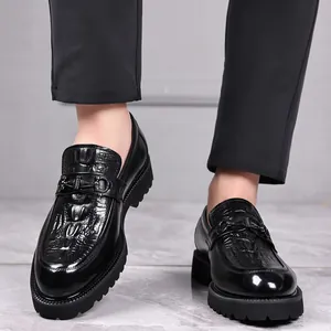Mocasines de hombre en cuero negro con textura de cocodrilo, hebilla metálica y suela dentada.