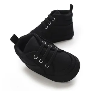 Détail de chaussures de marche bébé en toile noire avec semelle souple et lacets