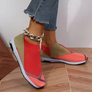 Gros plan de baskets en tricot rouges et kaki pour femmes portées avec une chevillère dorée.