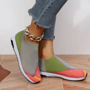 Gros plan de baskets en tricot multicolores et respirantes pour femmes portées aux pieds.